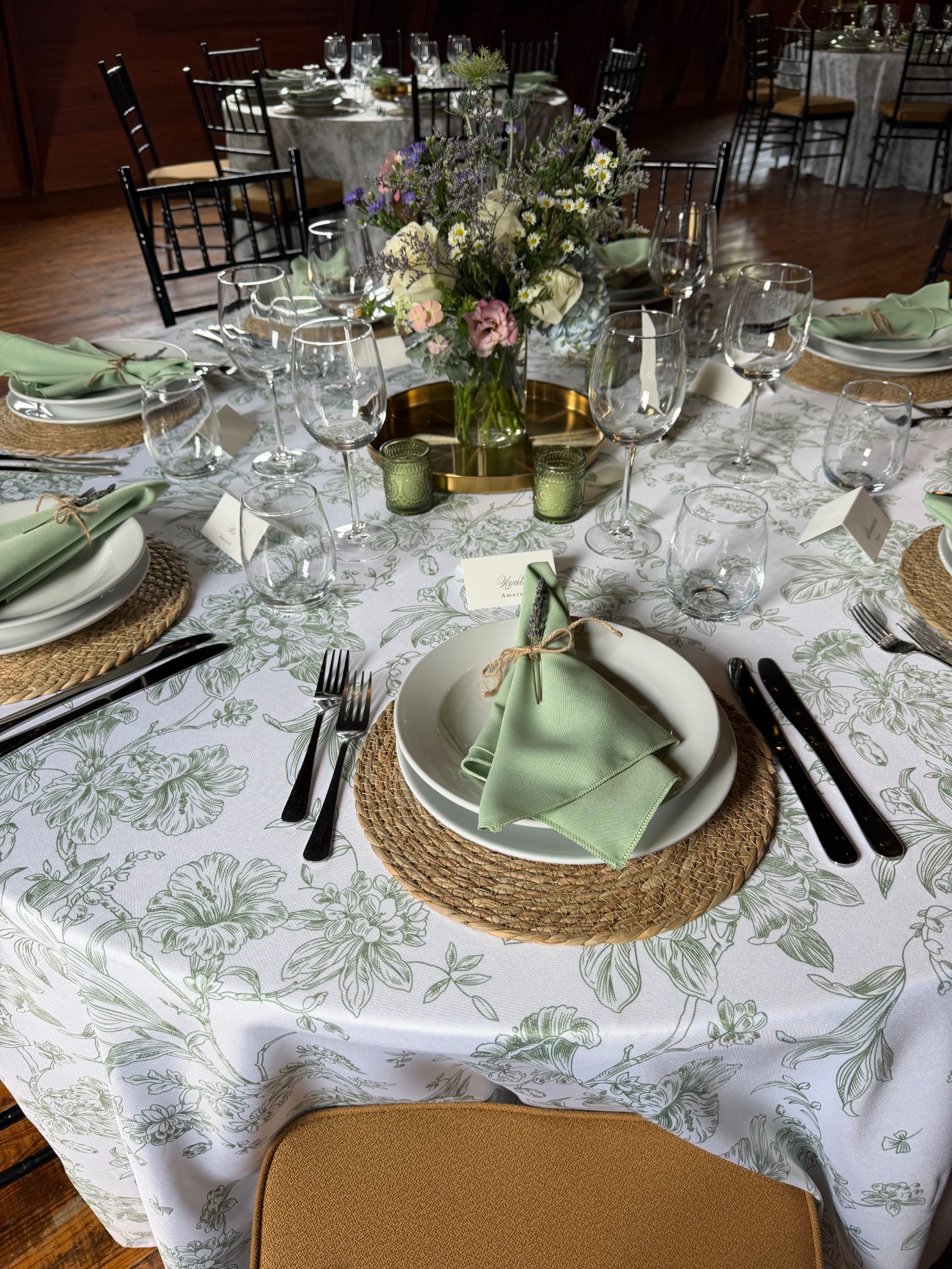 Sage floral linen with woven charger and folded green napkin